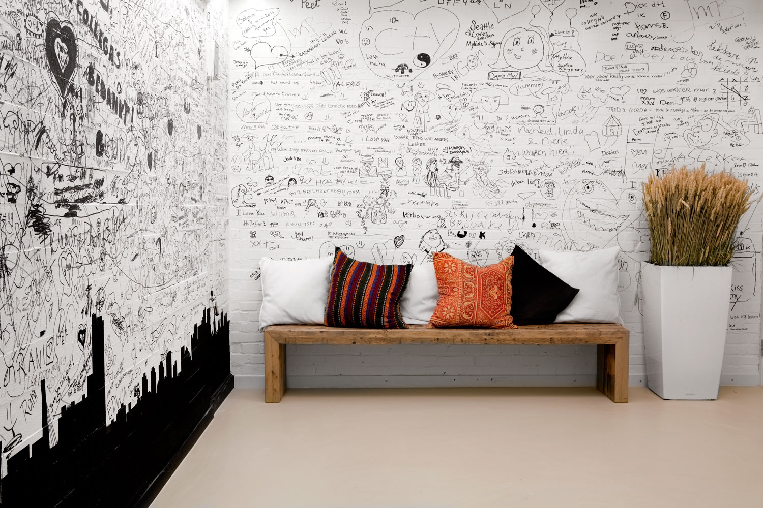 Bench with cushions in front of a hand-drawn illustrated wall